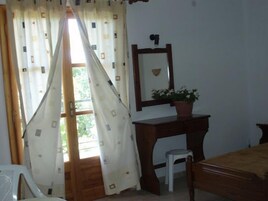 Una habitación con un escritorio de madera, un taburete pequeño, un espejo y una planta en maceta.