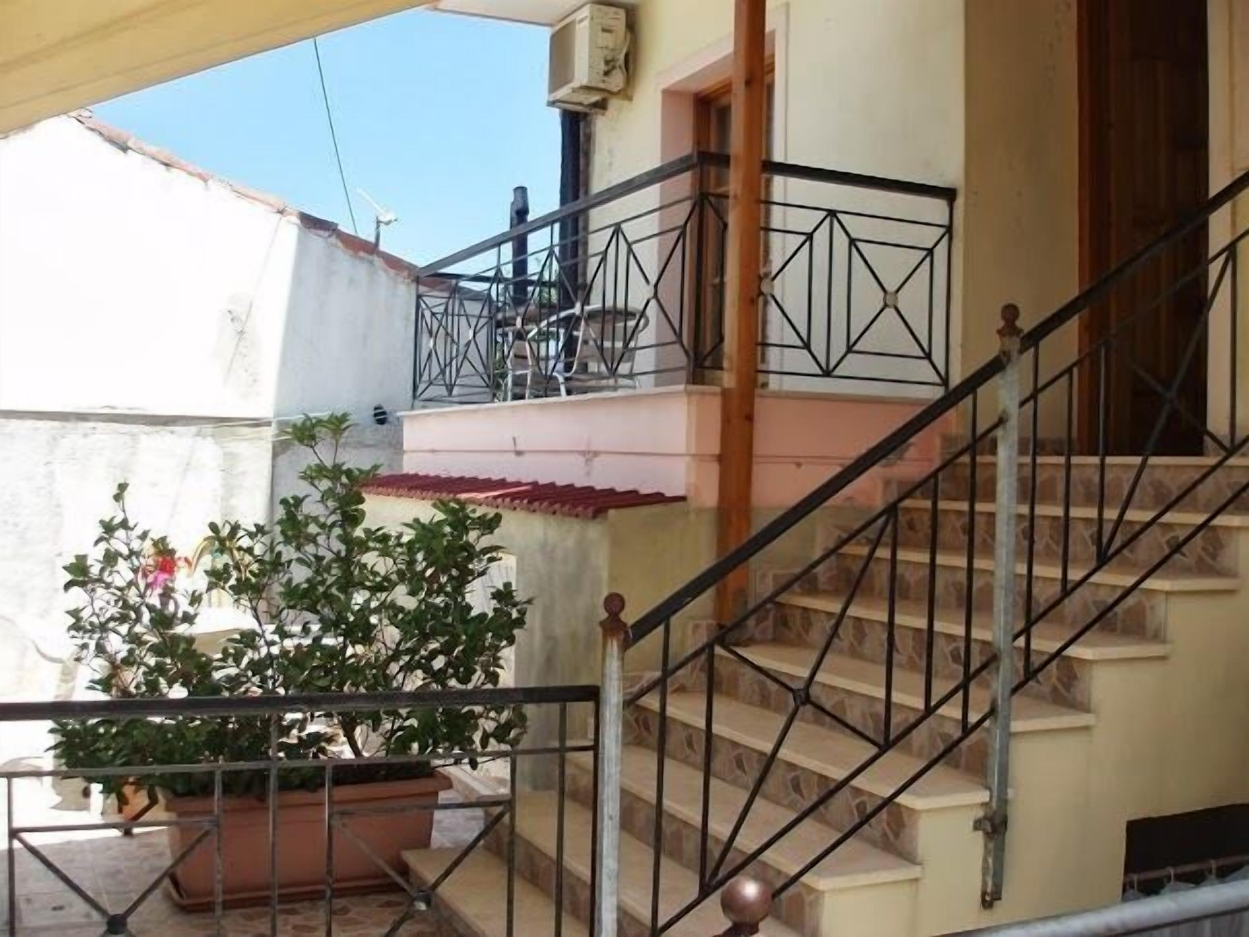 A staircase with a metal railing leading to a balcony.