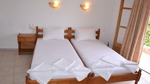 A double bed with white linens and two bedside tables, each with a lamp. - Hellen Studios (Skiathos)