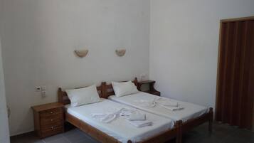 A simple, clean room with a double bed, wooden headboard, two bedside tables, and a small dresser.