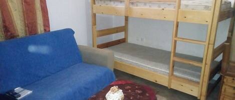 A bunk bed with a blue sofa and a small table with a cake.