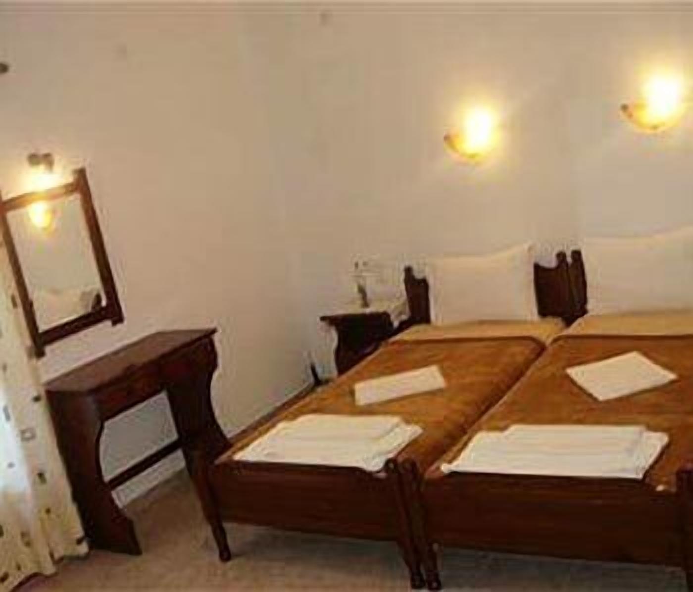 Ein Zimmer mit zwei Holzbetten, einem Nachttisch, einem Spiegel und Wandleuchten.