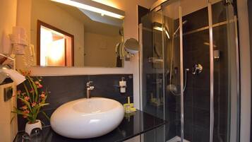 A modern bathroom with a white sink, a glass-enclosed shower, and a large mirror.
