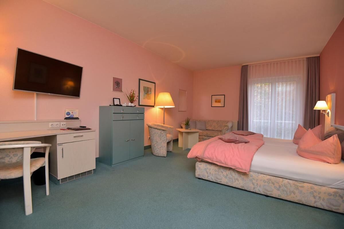 Habitación de hotel con cama, escritorio, silla y televisión.