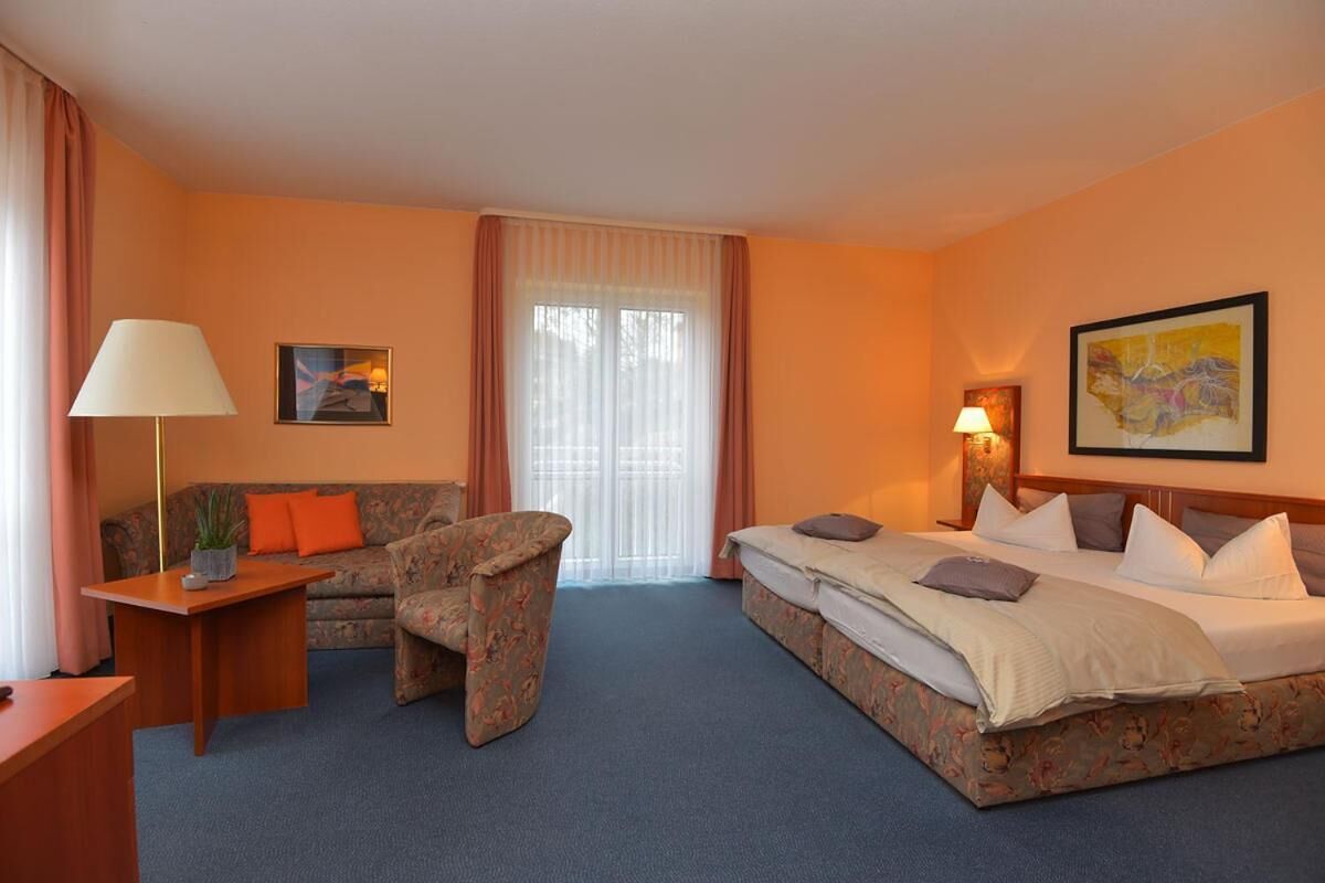 Una camera d'albergo con un letto, un divano, una sedia, una scrivania e una lampada.