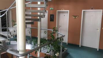 Un interno a più livelli con una scala a chiocciola, un pavimento rivestito di moquette verde e diverse porte, inclusa un'uscita di sicurezza.