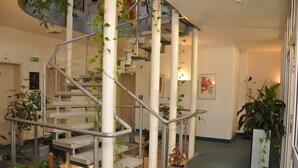 A multi-level indoor staircase with metal railings and stone steps, surrounded by potted plants and artwork. - Altstadthotel An Der Werra (Meiningen)