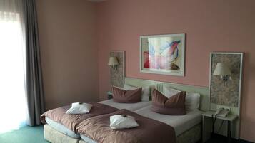 Hotelkamer met een tweepersoonsbed, twee nachtkastjes, een schilderij aan de muur en een raam met gordijnen.
