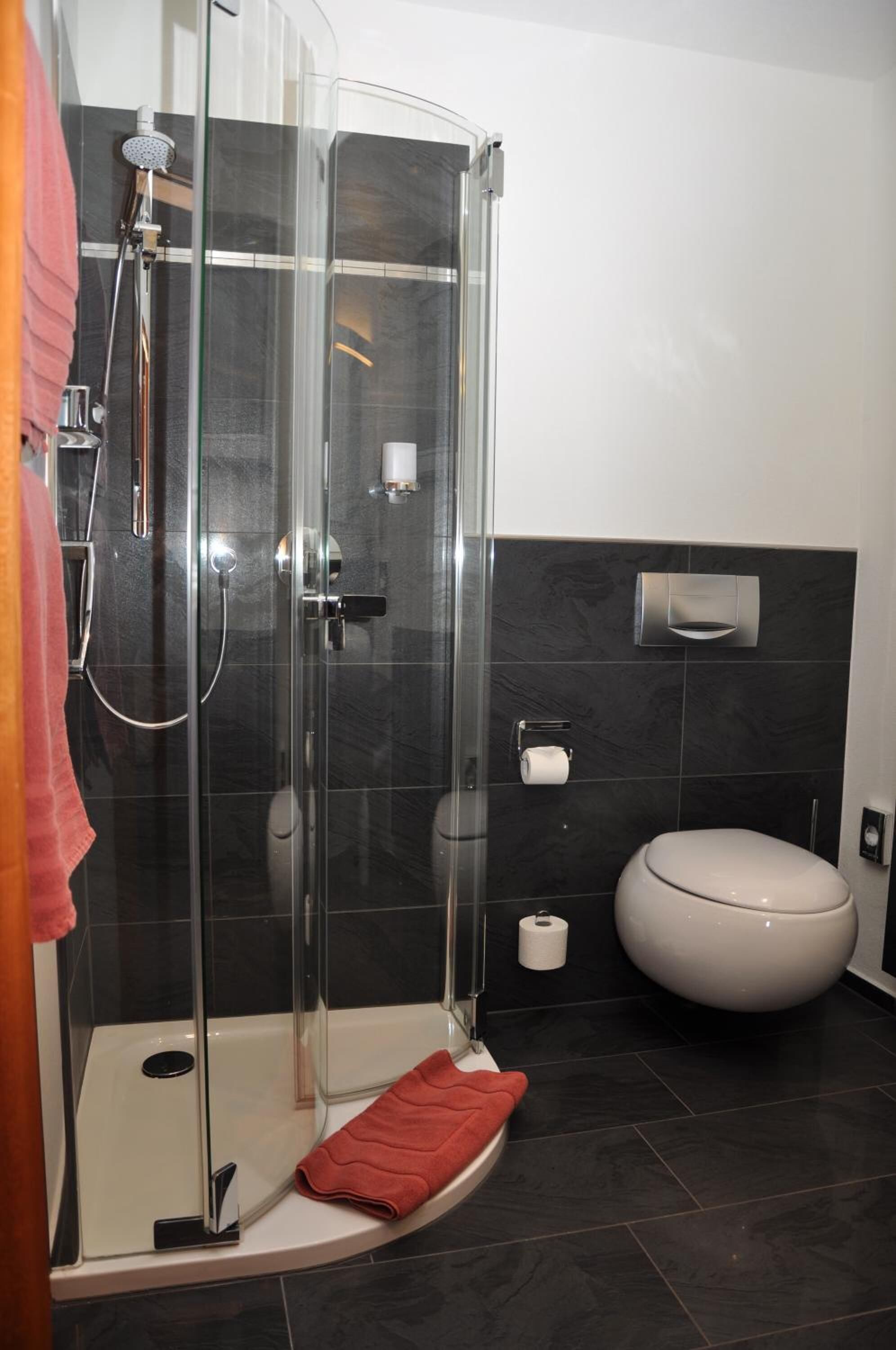 Un baño moderno con ducha de vidrio, inodoro y toallero.