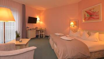 Habitación de hotel con cama, escritorio, silla, televisor y un cuadro en la pared.
