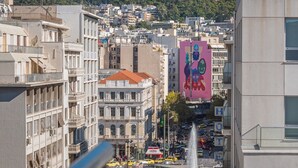 A cityscape with a prominent hill in the background, modern buildings, and a fountain in the center. - Diros Hotel (Athens)
