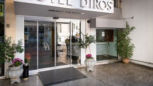 A hotel entrance with a glass door, a sign reading "HOTEL DIROS," and potted plants. - Diros Hotel (Athens)