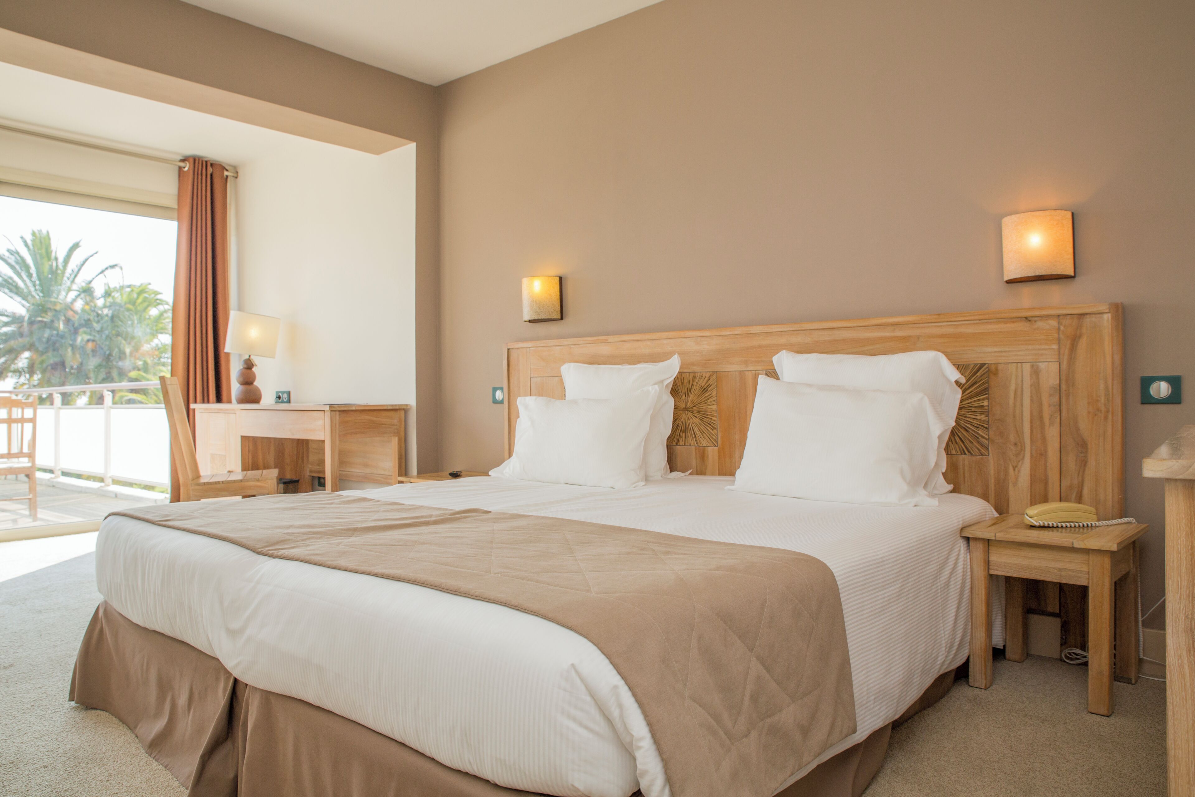 Habitación de hotel con una cama grande, dos mesitas de noche, un escritorio y una silla.
