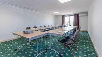 A conference room with a long table, chairs, a projector, and a carpeted floor.