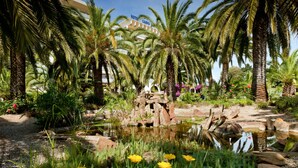 A hotel with a tropical garden, palm trees, and a pond. - Campo Dell'Oro (Ajaccio)