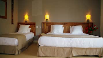 A hotel room with two beds, beige bedding, and wall-mounted lamps.
