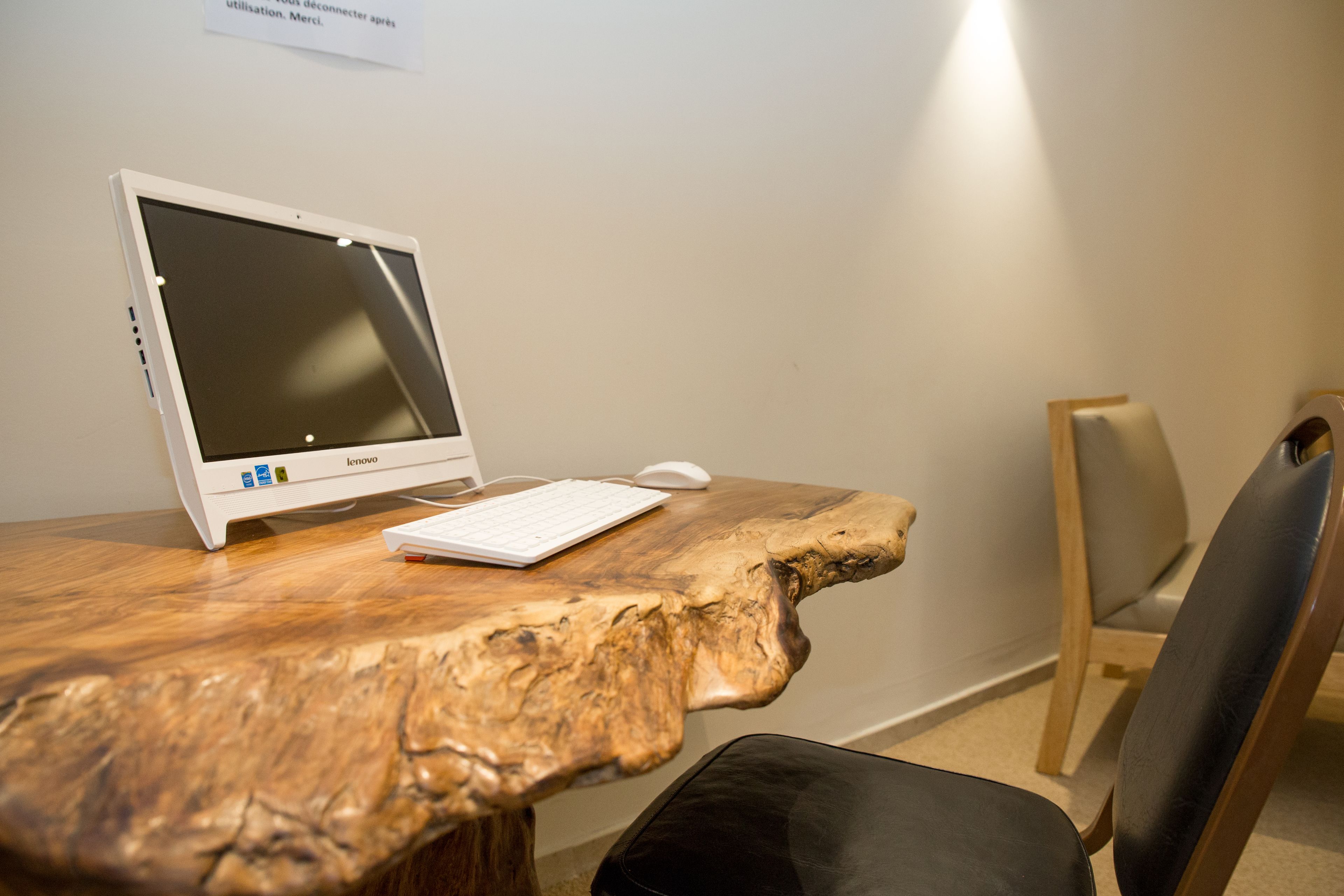 Una mesa de madera con una computadora portátil y un ratón, una silla, y un cartel en la pared.