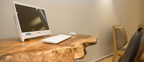 Una mesa de madera con una computadora portátil y un ratón, una silla, y un cartel en la pared.