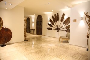A lobby with a polished floor, a wooden door, and a wall-mounted art piece.