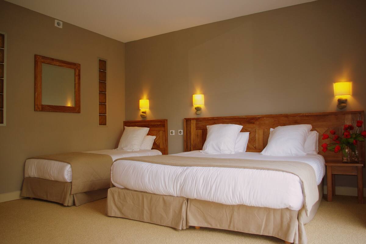 Ein Hotelzimmer mit zwei Betten, beigen Wänden und einem hölzernen Kopfteil.