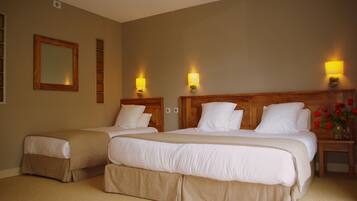Habitación de hotel con dos camas, paredes color beige y cabecera de madera.