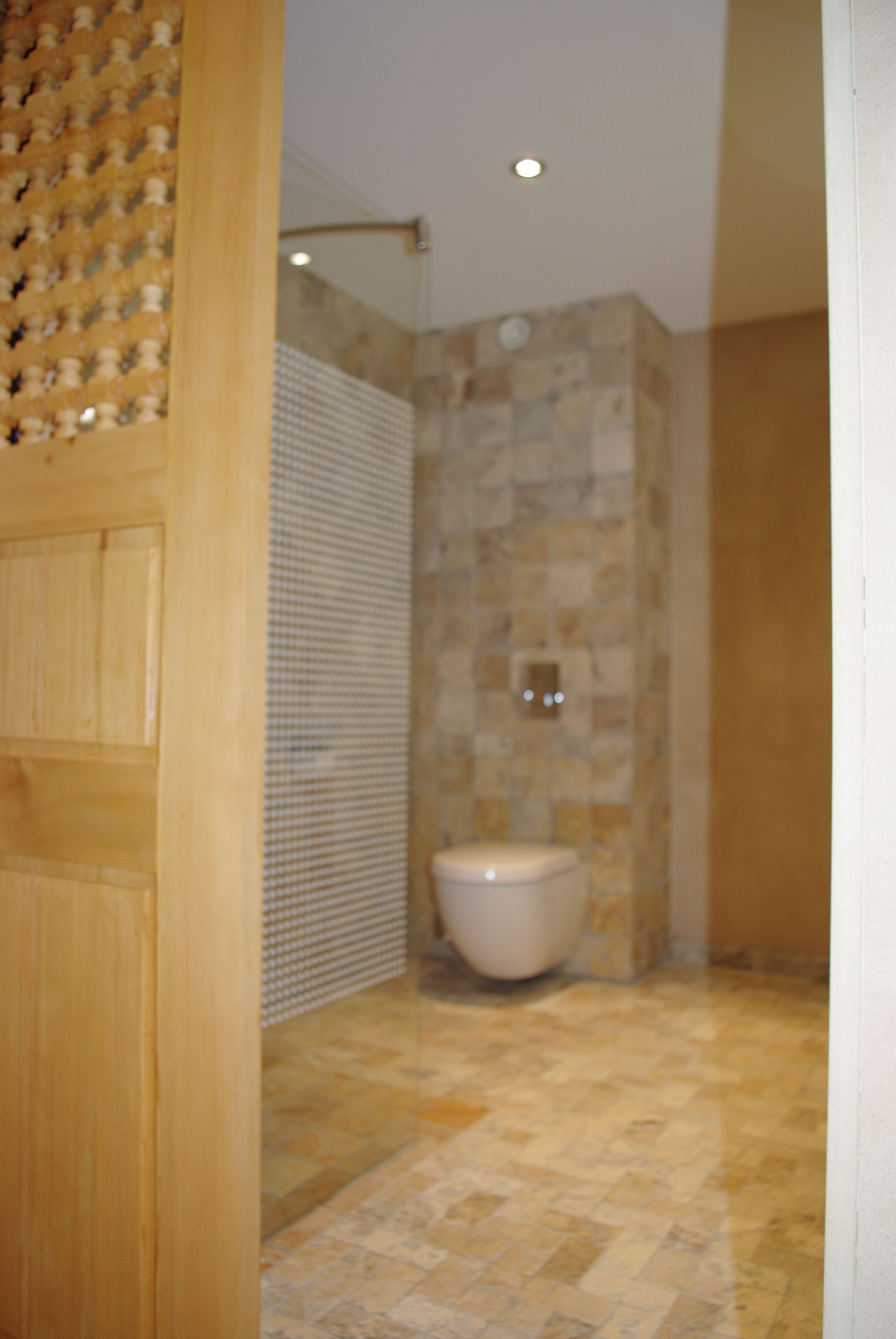 A bathroom with a tiled floor, a toilet, and a shower area.