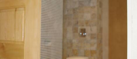 A bathroom with a tiled floor, a toilet, and a shower area.