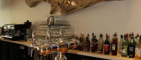 A bar area with a wooden countertop, a large piece of driftwood decor, and a variety of liquor bottles and glasses.
