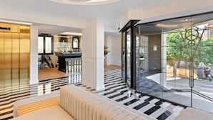 A modern hotel lobby with a black and white striped floor, a large chandelier, and a seating area. - Hotel San Carlu Citadelle (Ajaccio)