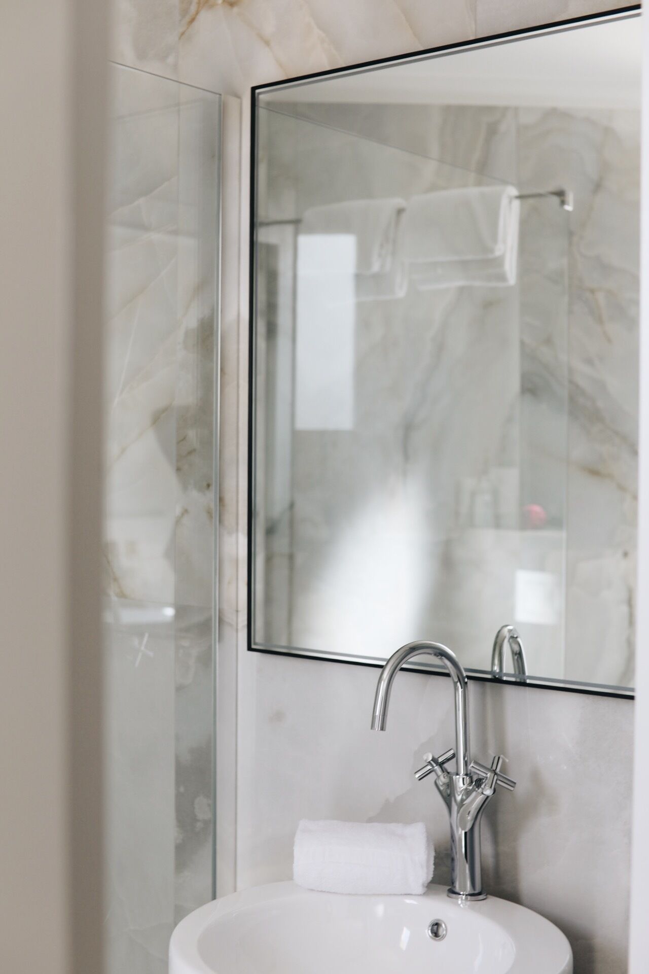 Une salle de bain avec une douche à parois de verre, un lavabo blanc et un grand miroir.