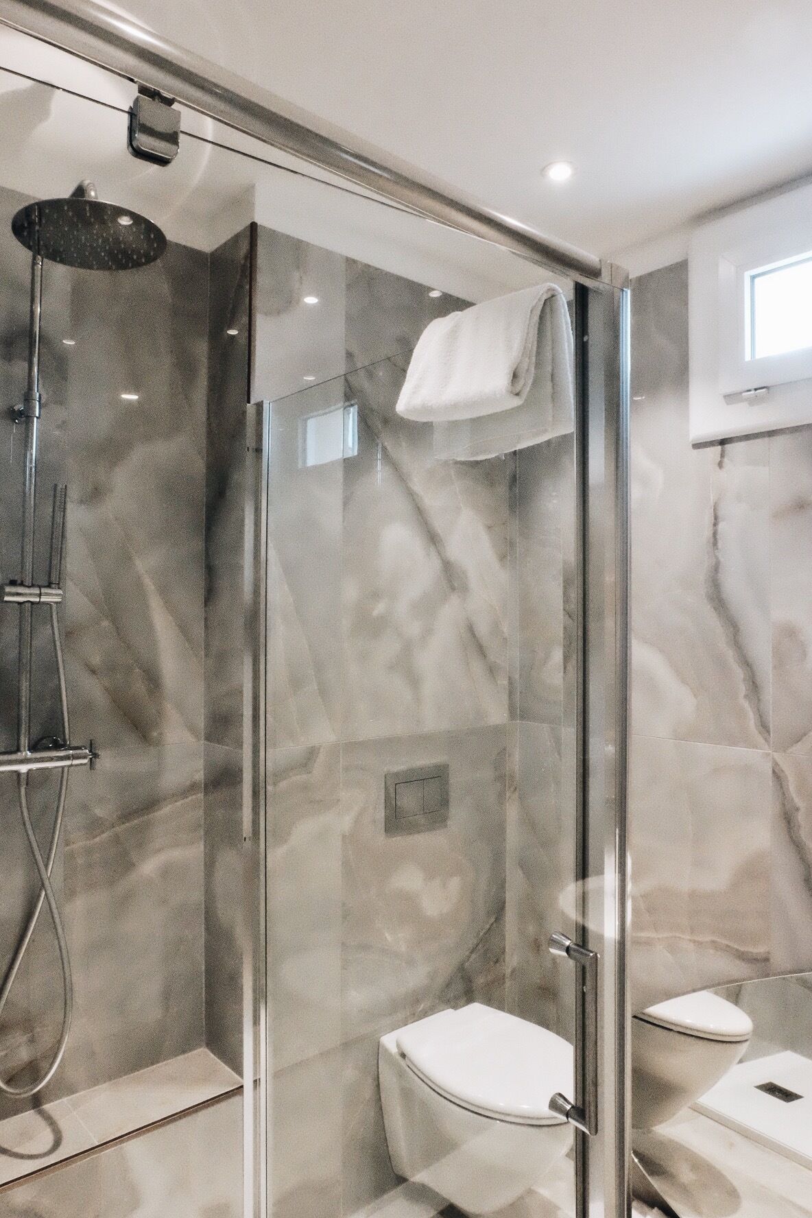 Uma casa de banho moderna com chuveiro em cabine de vidro, sanita e lavatório.
