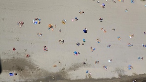 Vista aérea de una playa con gente y sombrillas.