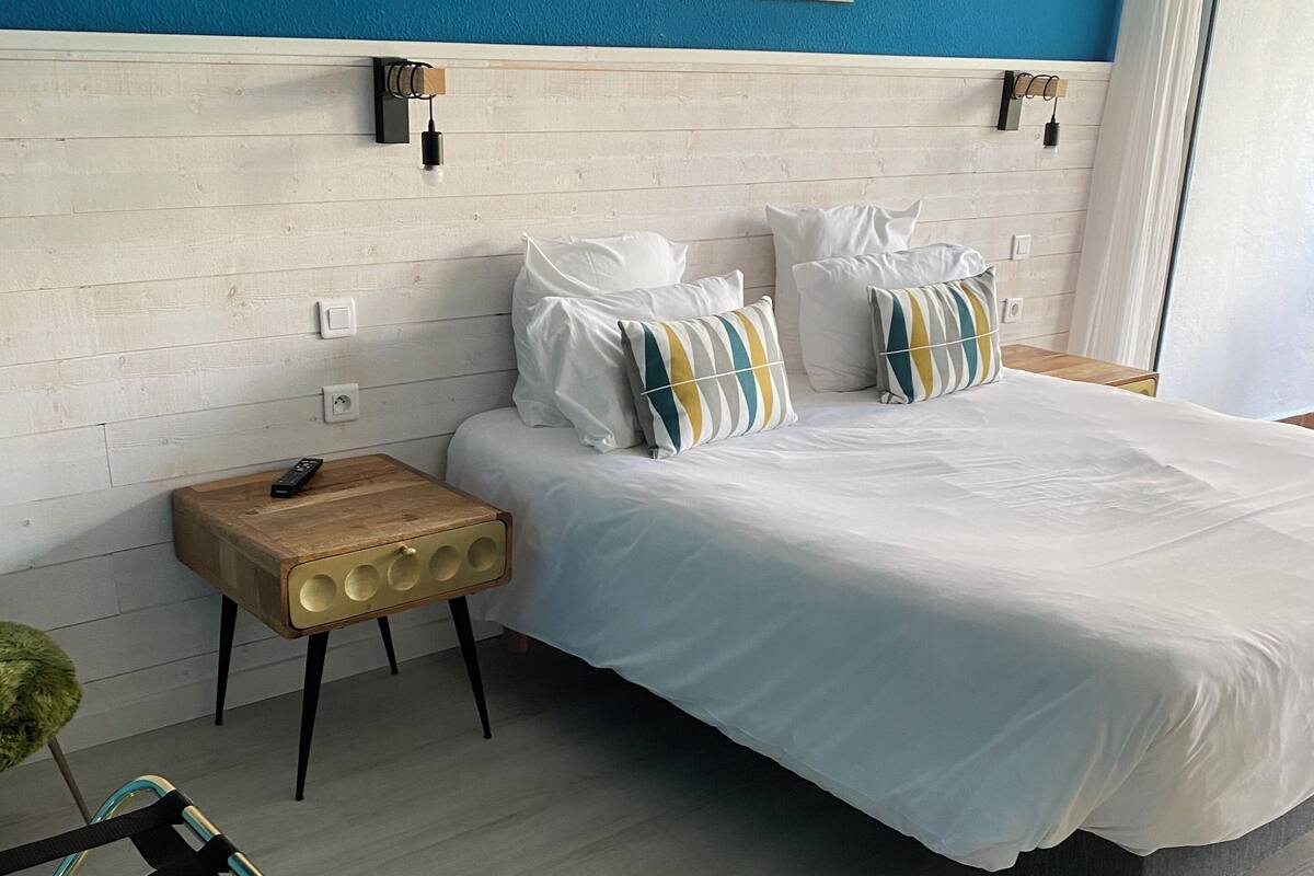 A bedroom with a bed, bedside tables, a chair, and a painting on the wall.