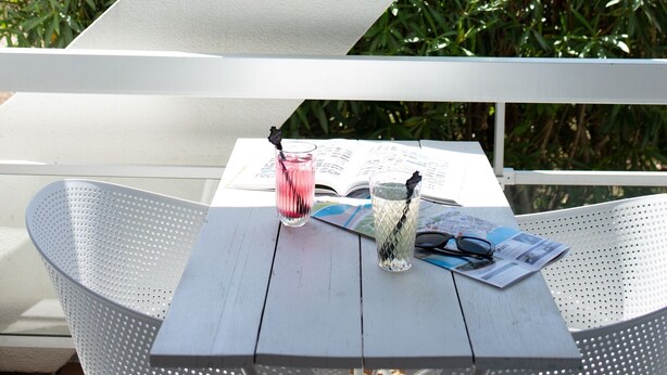 A white table with a glass of water, a pair of sunglasses, and a menu.