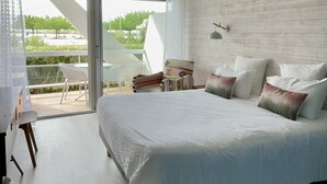 Un dormitorio moderno con una cama grande, un balcón con vistas y una pared de ladrillo blanco.