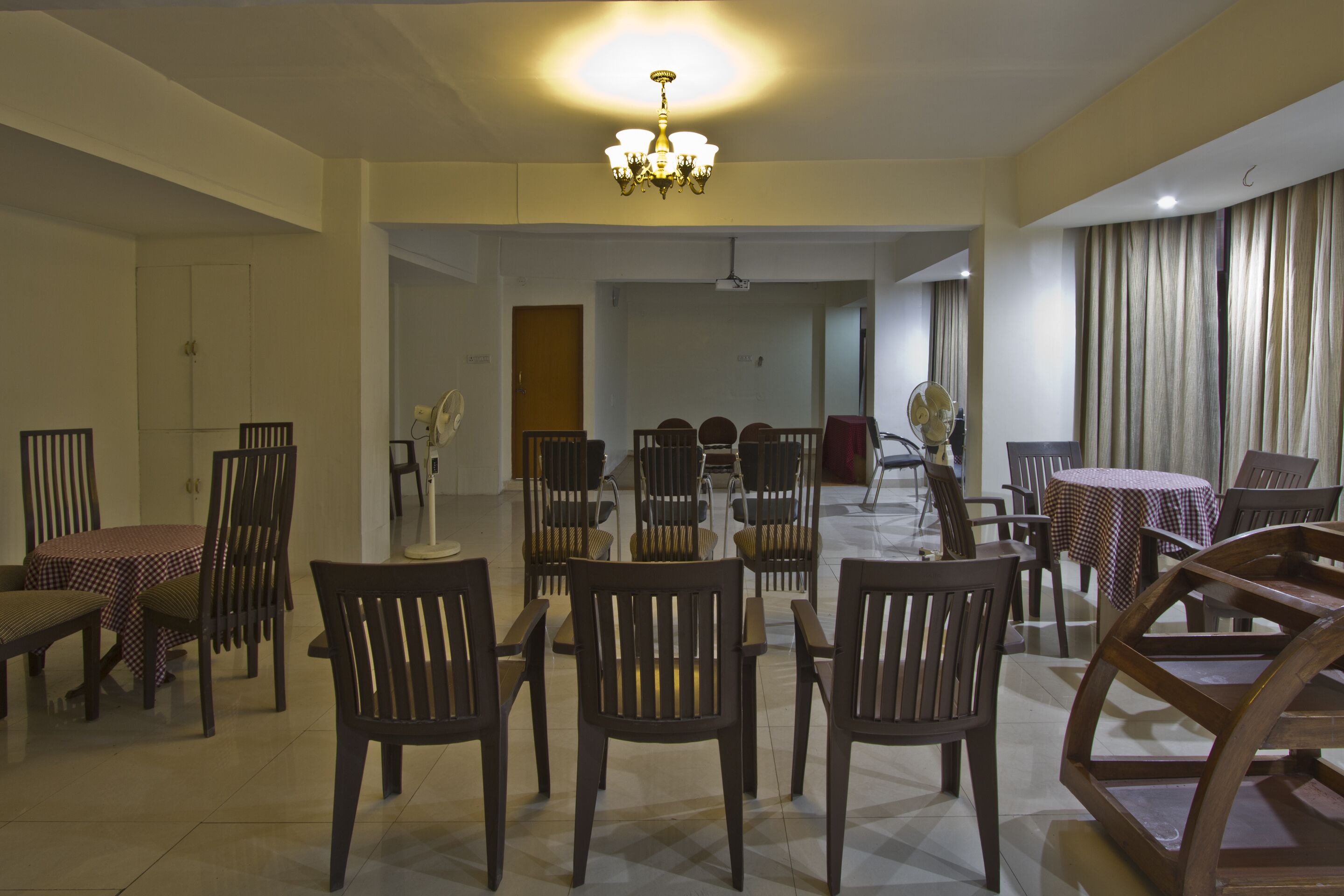 A dining area with a chandelier, multiple dining tables, and chairs.