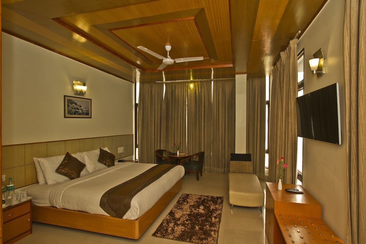 A hotel room with a bed, a desk, a chair, a TV, and a ceiling fan.