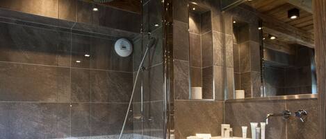 A modern bathroom with a glass-enclosed shower, a large mirror, and a granite countertop.