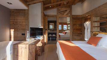 A wooden interior with a bed, a TV, and a desk.