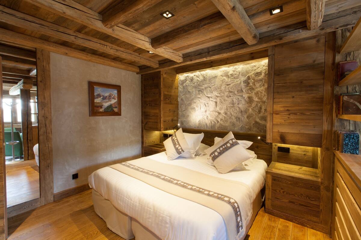 Ein Schlafzimmer mit Holzrahmen, einem großen Bett, einer Wand mit Steinakzenten und einem gerahmten Bild.
