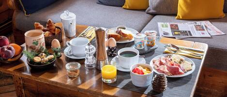 Una mesa de desayuno con croissants, huevos, fruta y café.