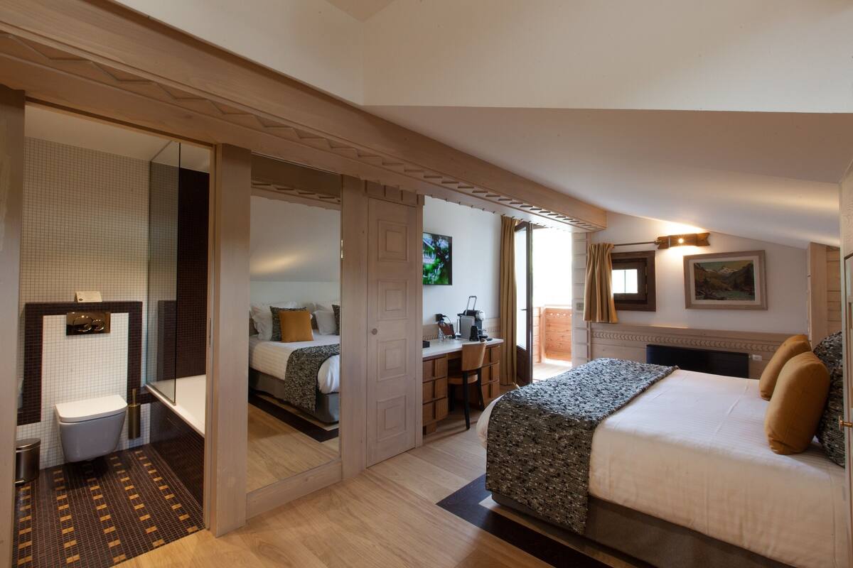 Ein Hotelzimmer mit Bett, Schreibtisch und einem Badezimmer mit Toilette und Waschbecken.