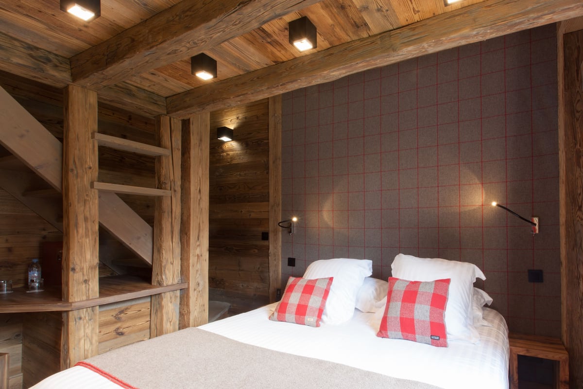 Ein Holzhütten-Interieur mit einem Bett, einer Holztreppe und einer Wand mit Rutenmuster.