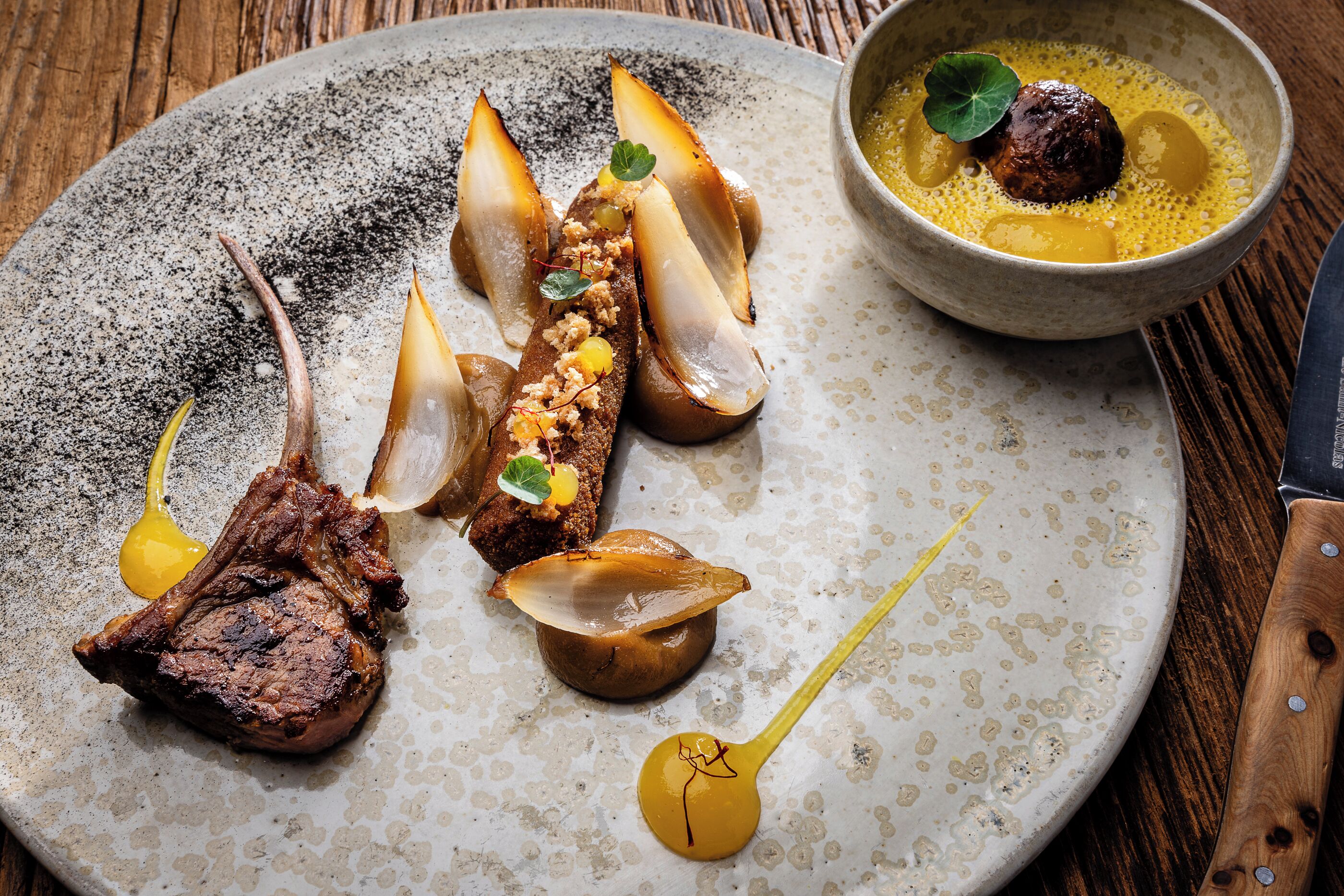 Une assiette contenant un steak, des champignons et un petit bol de sauce.