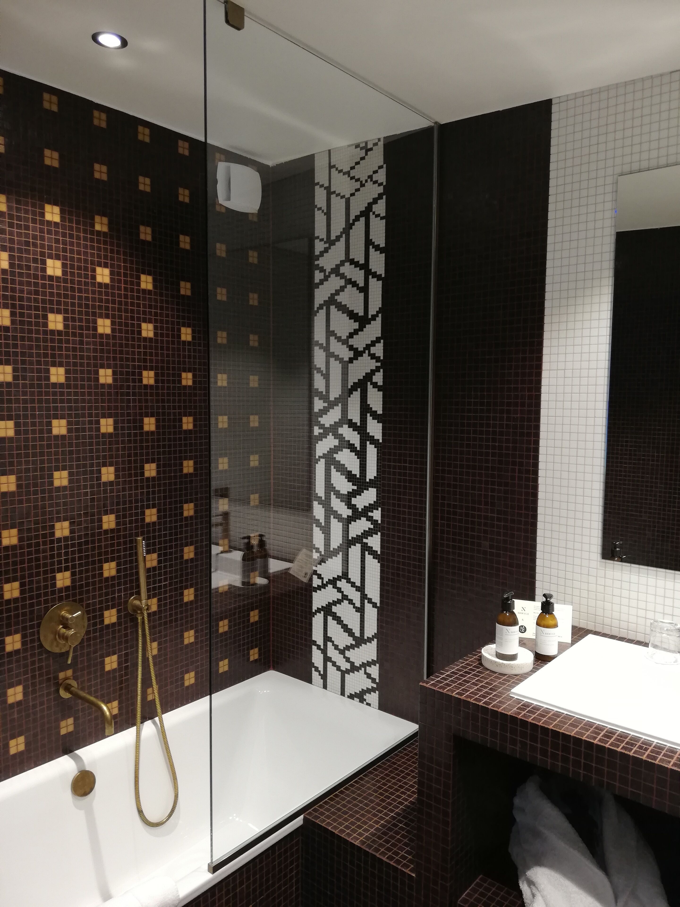 Un baño moderno con ducha envuelta en vidrio, una bañera blanca y un tocador con espejo.
