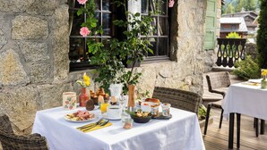 Una mesa de desayuno dispuesta con diferentes platos, un florero con flores y una ventana que ofrece vistas del entorno.