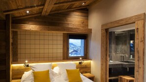Un dormitorio con una cama grande, cabecero de madera, ventana con vistas y una puerta de madera.