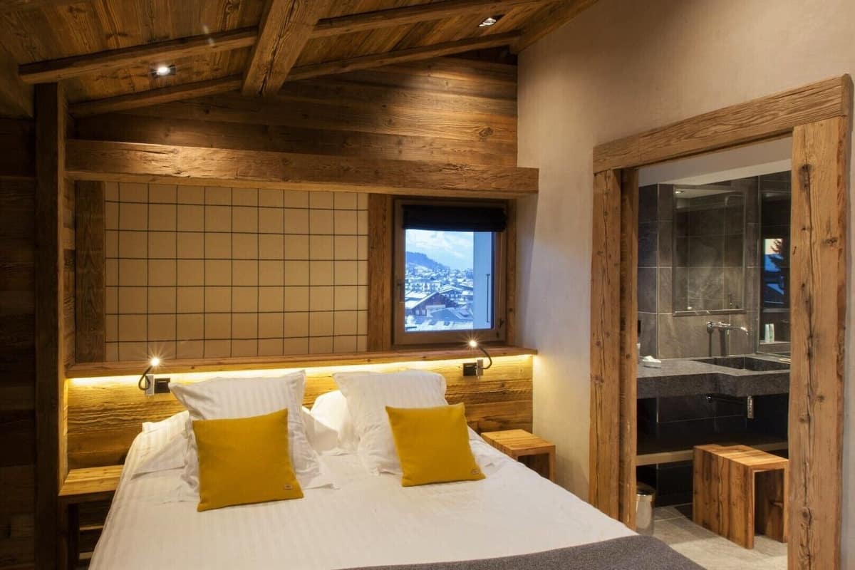 Ein Schlafzimmer mit einem großen Bett, einem Holzkopfende, einem Fenster mit Aussicht und einer Holztür.