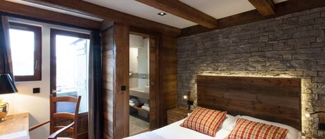 A bedroom with a stone wall, wooden headboard, and a bed with two pillows.