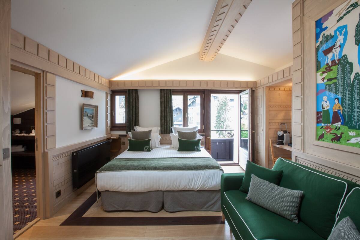 Ein Schlafzimmer mit einem großen Bett, einem grünen Sofa und einem Bild an der Wand.